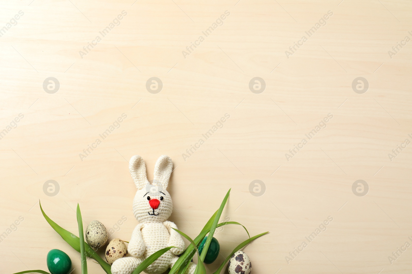 Photo of Flat lay composition of Easter bunny toy and eggs on wooden background, space for text