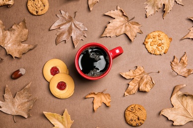 Flat lay composition with hot cozy drink and autumn leaves on color background