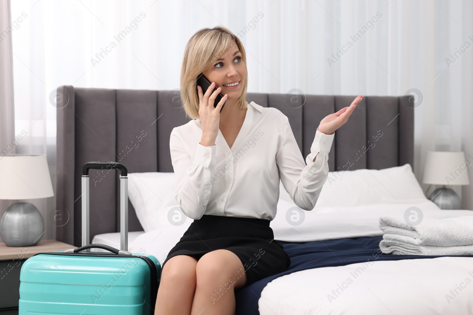 Photo of Smiling businesswoman talking on smartphone in stylish hotel room