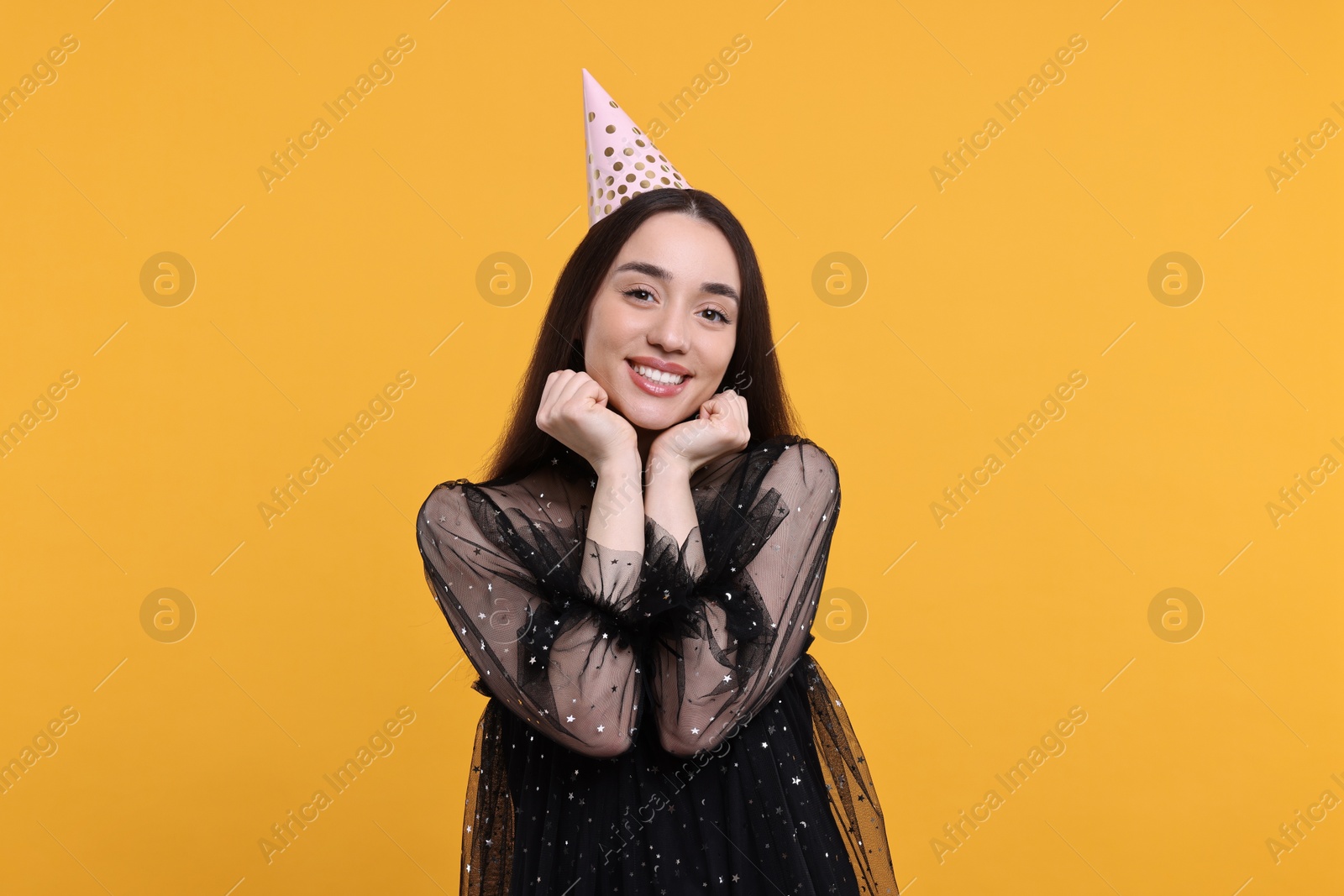 Photo of Happy woman in party hat on orange background