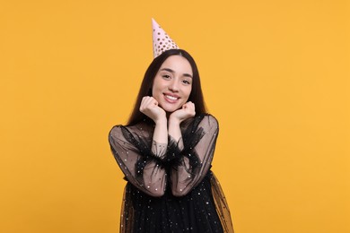 Happy woman in party hat on orange background