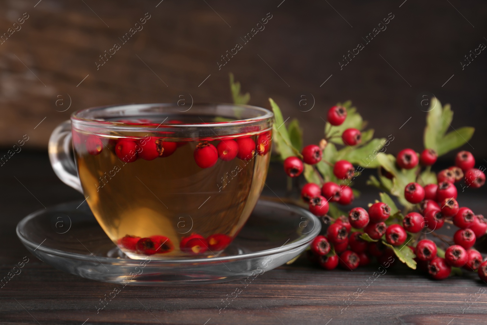 Photo of Cup of delicious immunity boosting tea with hawthorn on wooden table, closeup. Space for text