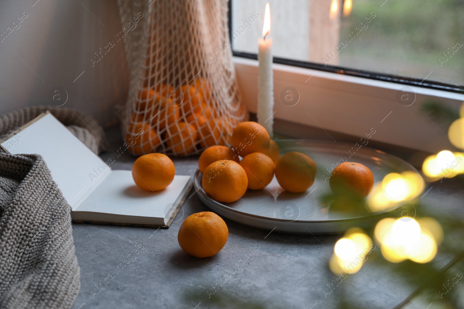 Photo of Fresh ripe tangerines and Christmas decor on grey table near window