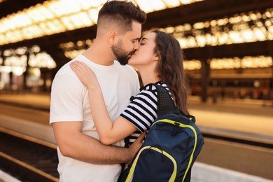 Long-distance relationship. Beautiful couple kissing on platform of railway station