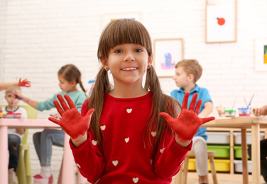 Photo of Cute little child with painted palms in room