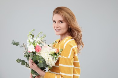 Photo of Beautiful woman with bouquet of flowers on grey background