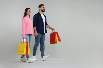 Photo of Happy couple with shopping bags on grey background. Space for text