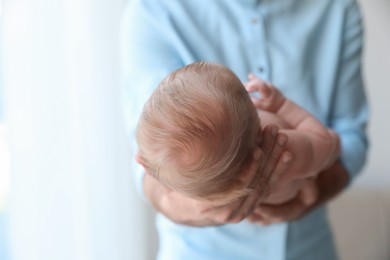 Father holding his newborn baby at home, closeup