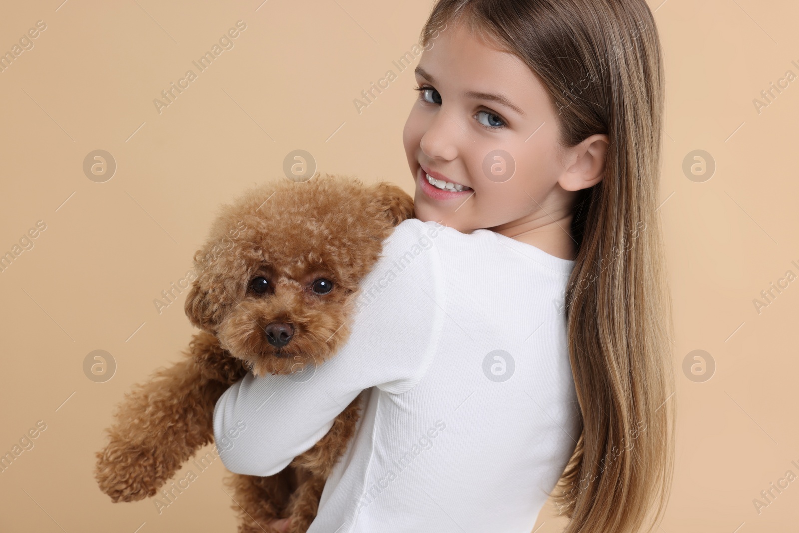 Photo of Little child with cute puppy on beige background. Lovely pet