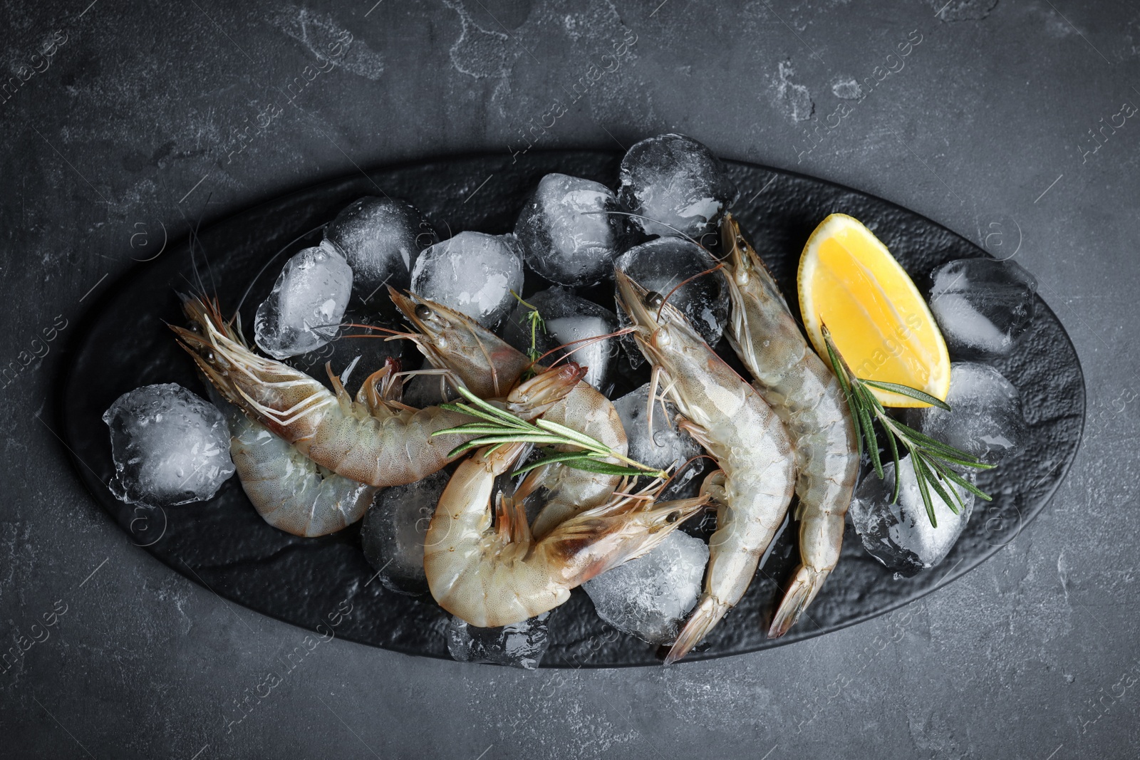 Photo of Raw shrimps with lemon slices and rosemary on grey table, top view