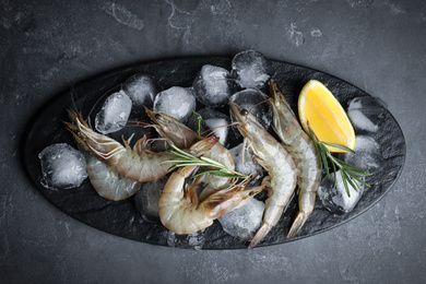 Photo of Raw shrimps with lemon slices and rosemary on grey table, top view