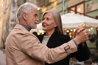 Affectionate senior couple dancing together on city street