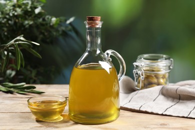 Jug and bowl of olive oil on wooden table. Healthy cooking