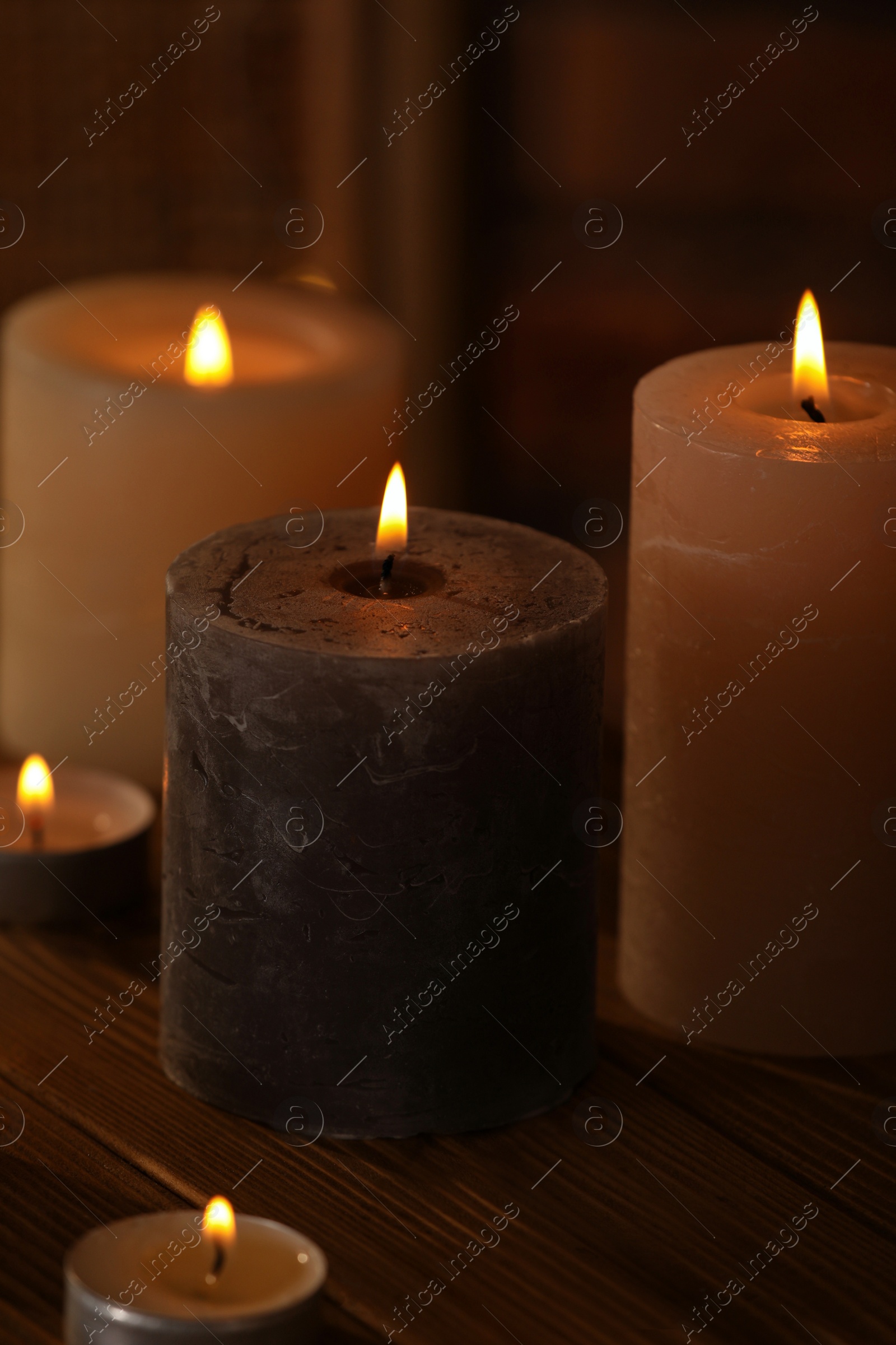 Photo of Spa composition with burning candles on wooden table in wellness center, closeup