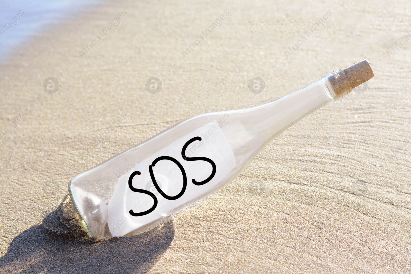 Photo of Glass bottle with SOS message on sand near sea