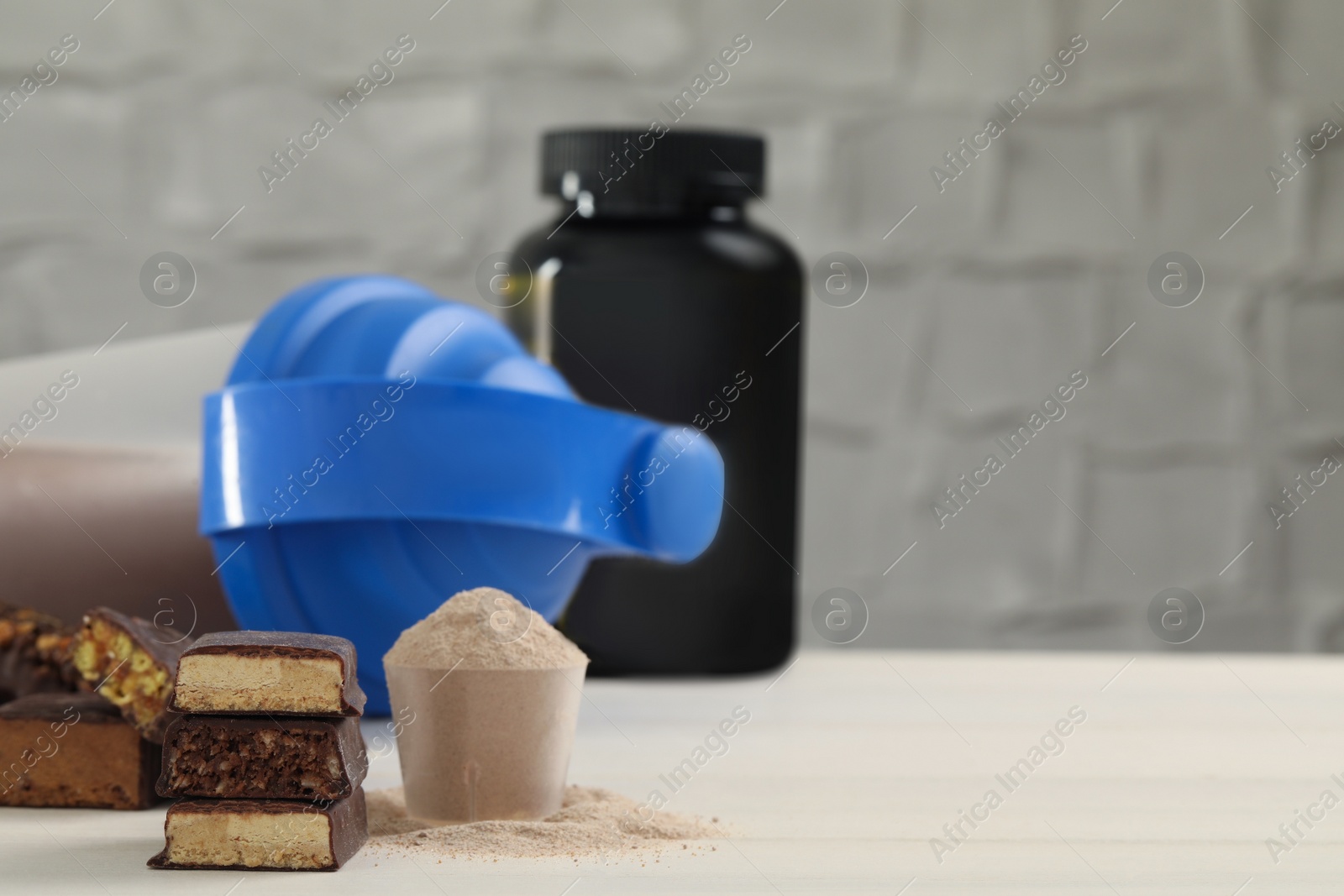 Photo of Different energy bars, protein cocktail and powder on white wooden table. Space for text