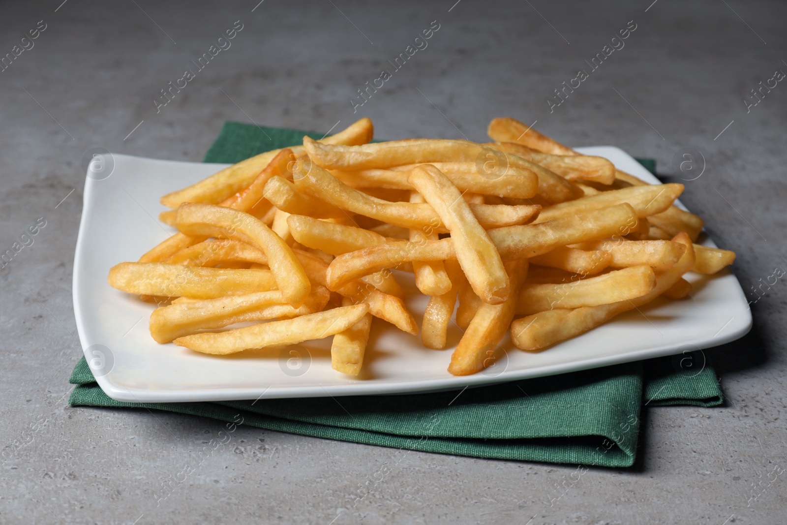 Photo of Plate of tasty french fries on grey table