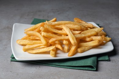 Plate of tasty french fries on grey table