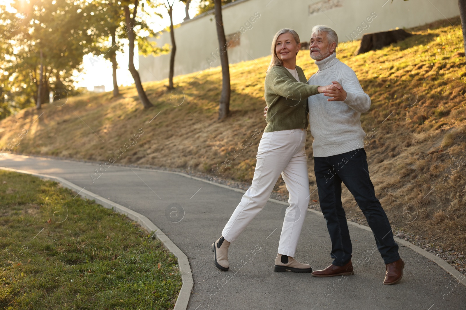 Photo of Affectionate senior couple dancing together outdoors, space for text