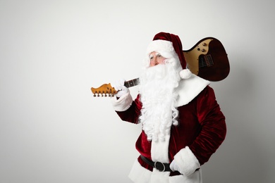 Santa Claus with electric guitar on light background, space for text. Christmas music