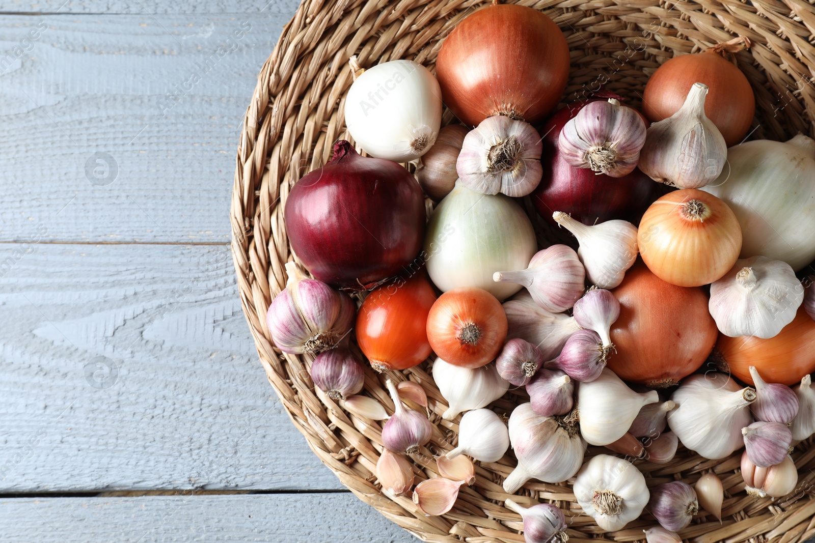 Photo of Fresh raw garlic and onions on gray wooden table, top view. Space for text