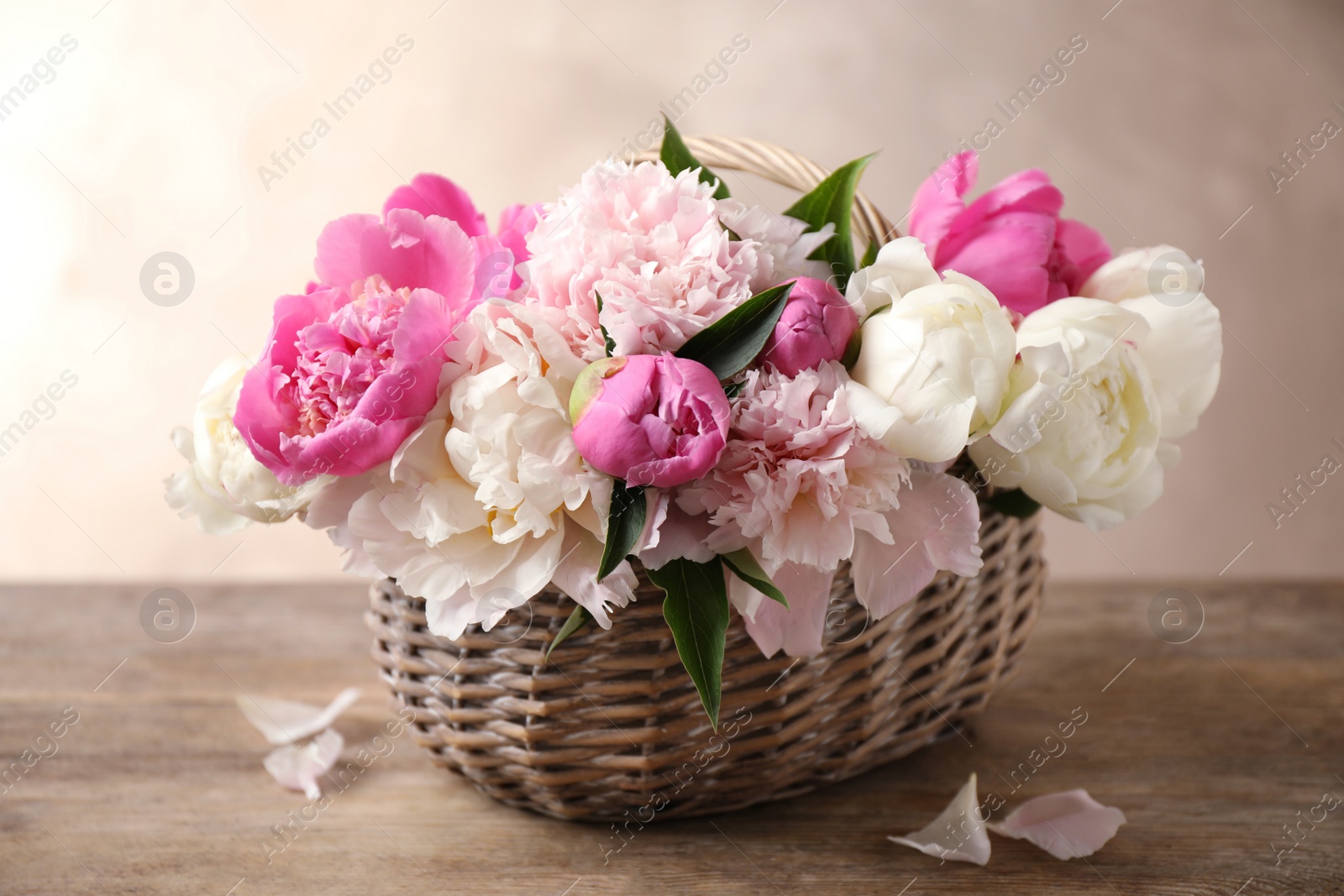 Photo of Beautiful peony bouquet in wicker basket on wooden table