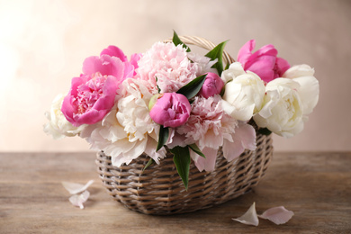 Photo of Beautiful peony bouquet in wicker basket on wooden table