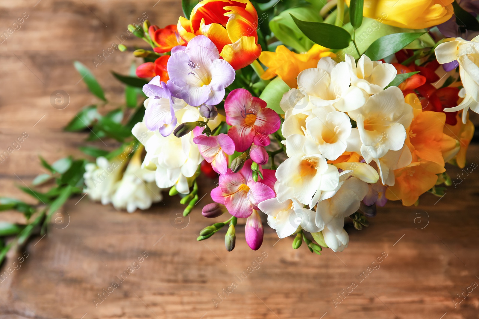 Photo of Beautiful bouquet of freesia flowers on table, closeup