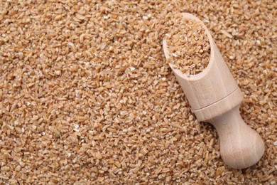 Photo of Wooden scoop with dry wheat groats, top view. Space for text