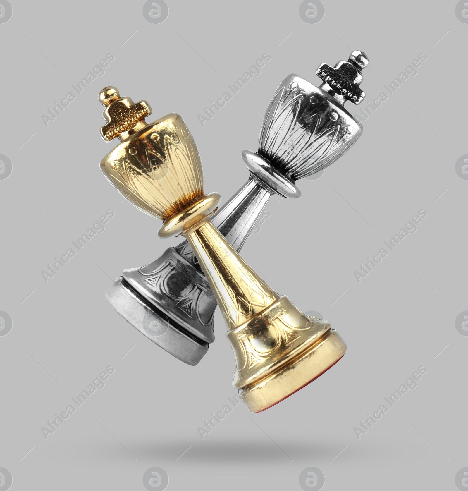 Image of Golden and silver chess kings in air on grey background