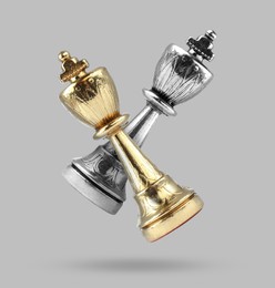 Golden and silver chess kings in air on grey background