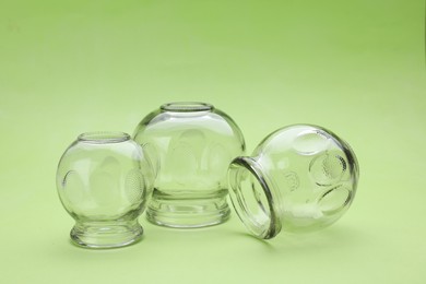 Glass cups on light green background. Cupping therapy