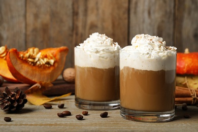 Glasses with tasty pumpkin spice latte on wooden table