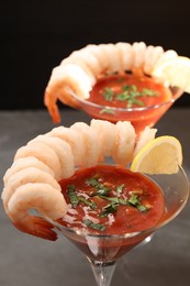 Tasty shrimp cocktail with sauce in glasses and lemon on grey table, closeup