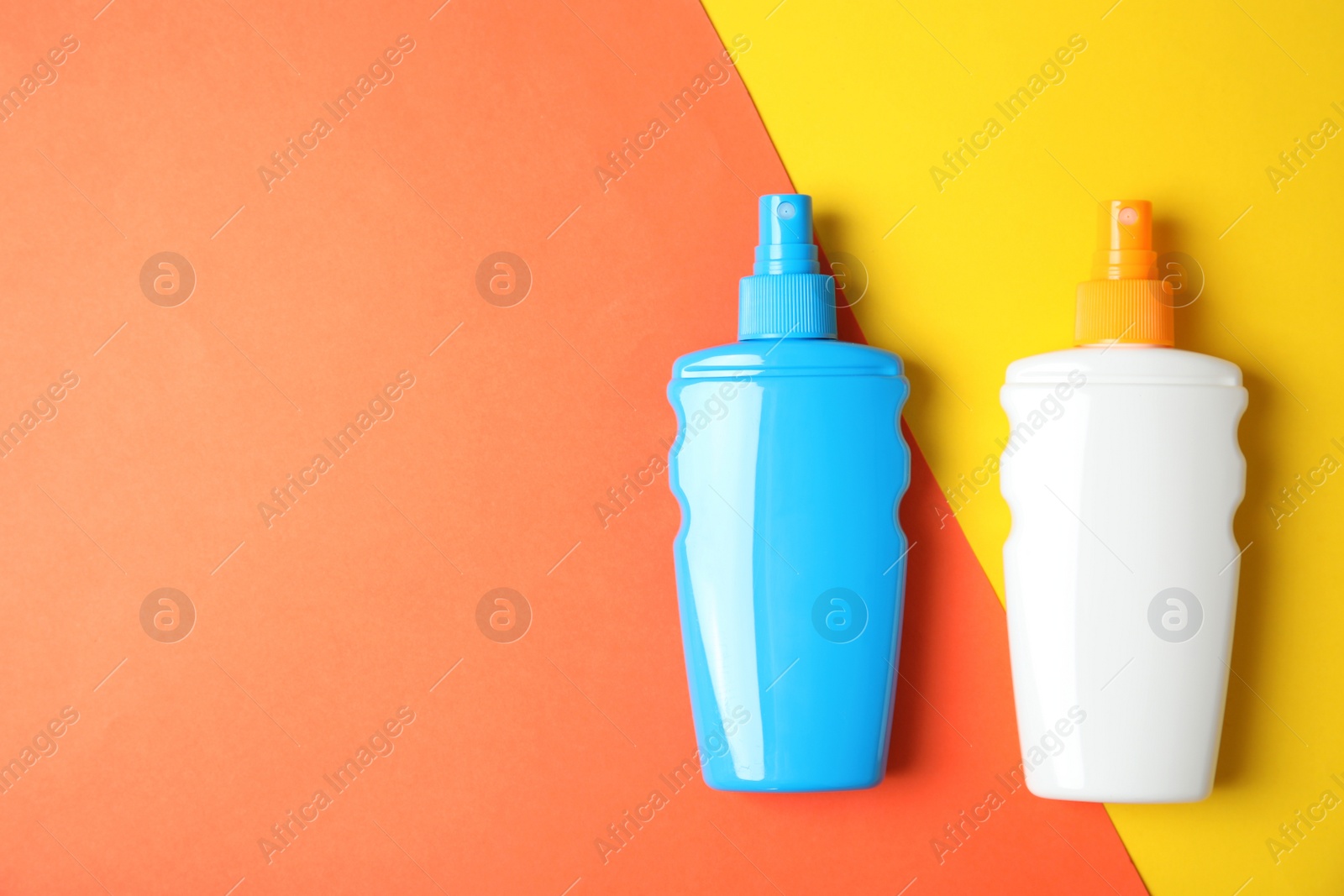 Photo of Bottles of sun protection body cream on color background, top view with space for text