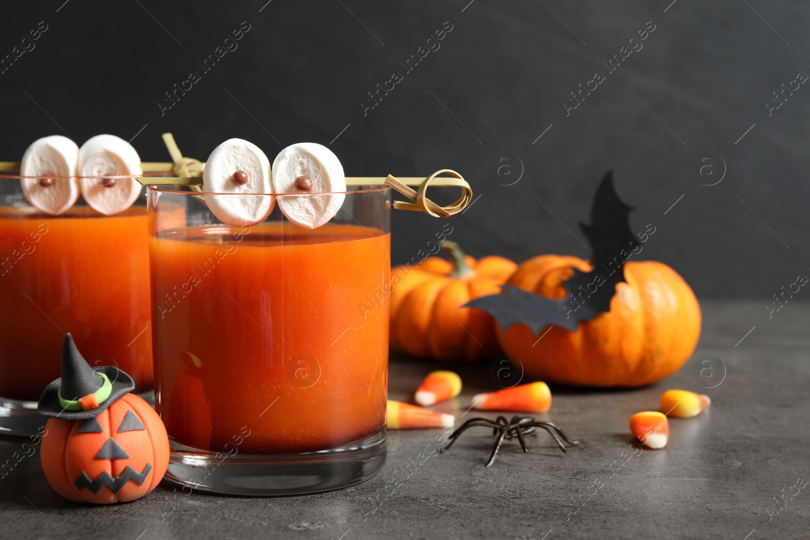 Photo of Decorated glasses with drinks on grey table, closeup. Halloween celebration