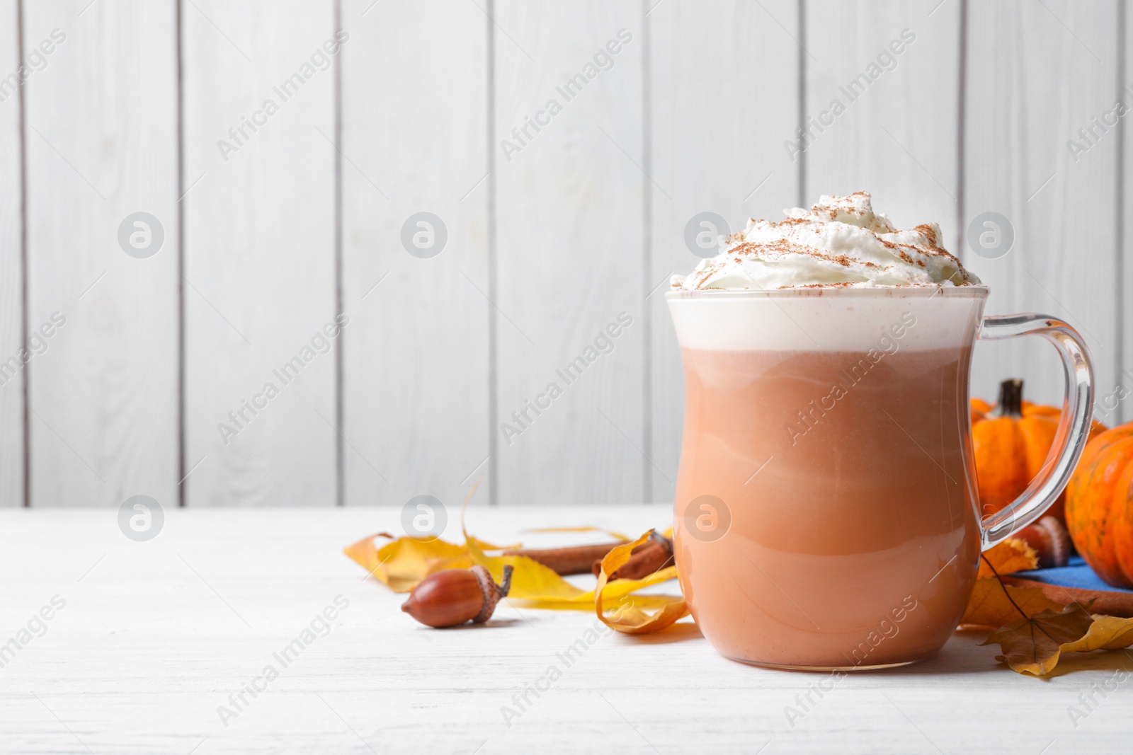 Photo of Delicious pumpkin latte on white table, closeup. Space for text