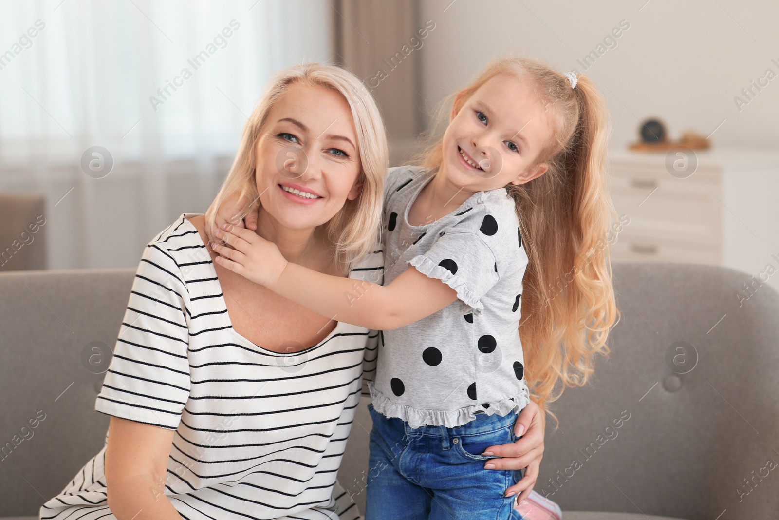 Photo of Portrait of mature woman and her granddaughter on sofa in living room