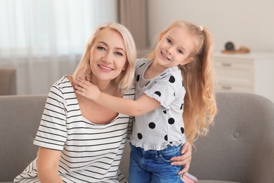 Portrait of mature woman and her granddaughter on sofa in living room