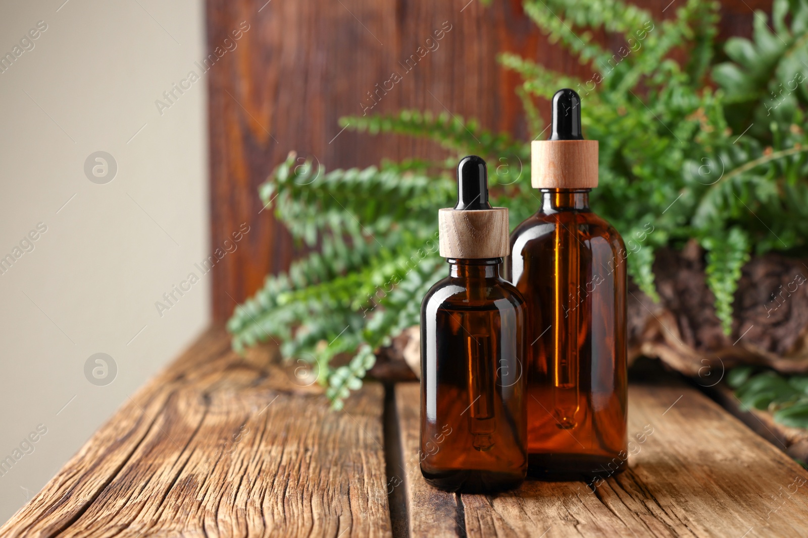 Photo of Glass bottles of essential oil on wooden table, space for text