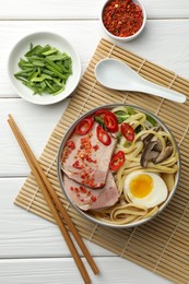 Photo of Delicious ramen in bowl served on white wooden table, flat lay. Noodle soup