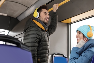 Photo of Young people listening to music with headphones in public transport