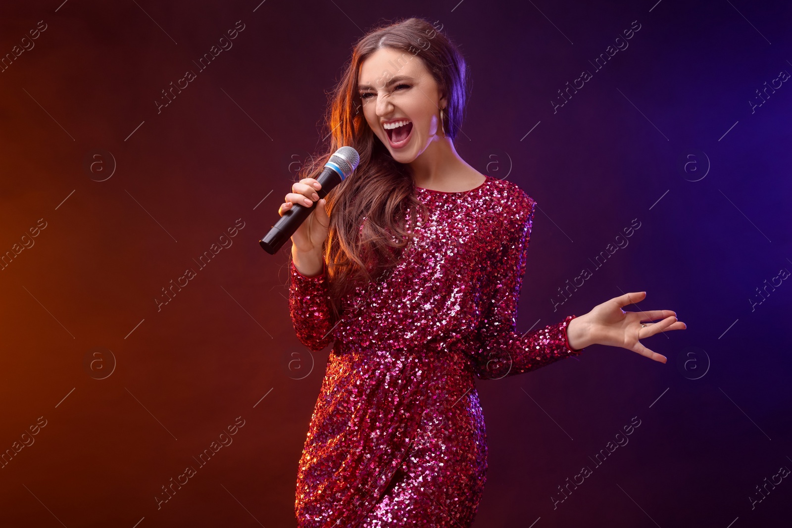 Photo of Emotional woman with microphone singing in color lights