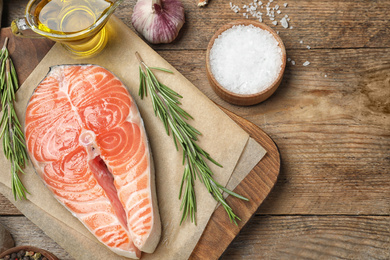 Flat lay composition with fresh raw salmon and products on wooden table. Fish delicacy