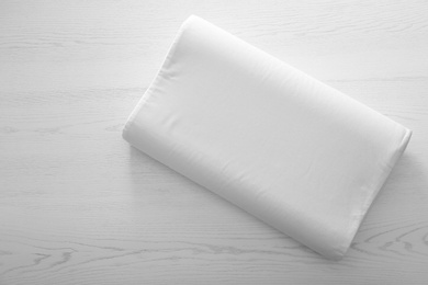 Photo of Soft bed pillow on wooden background, top view