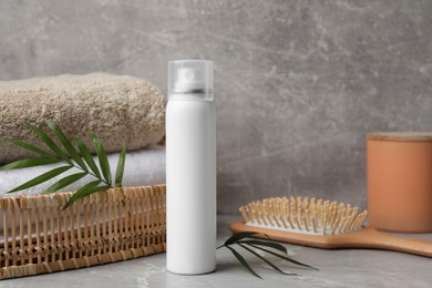 Photo of Dry shampoo spray, towels and wooden hairbrush on light grey table
