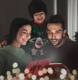 Happy family opening gift box with magical light at home. Christmas celebration