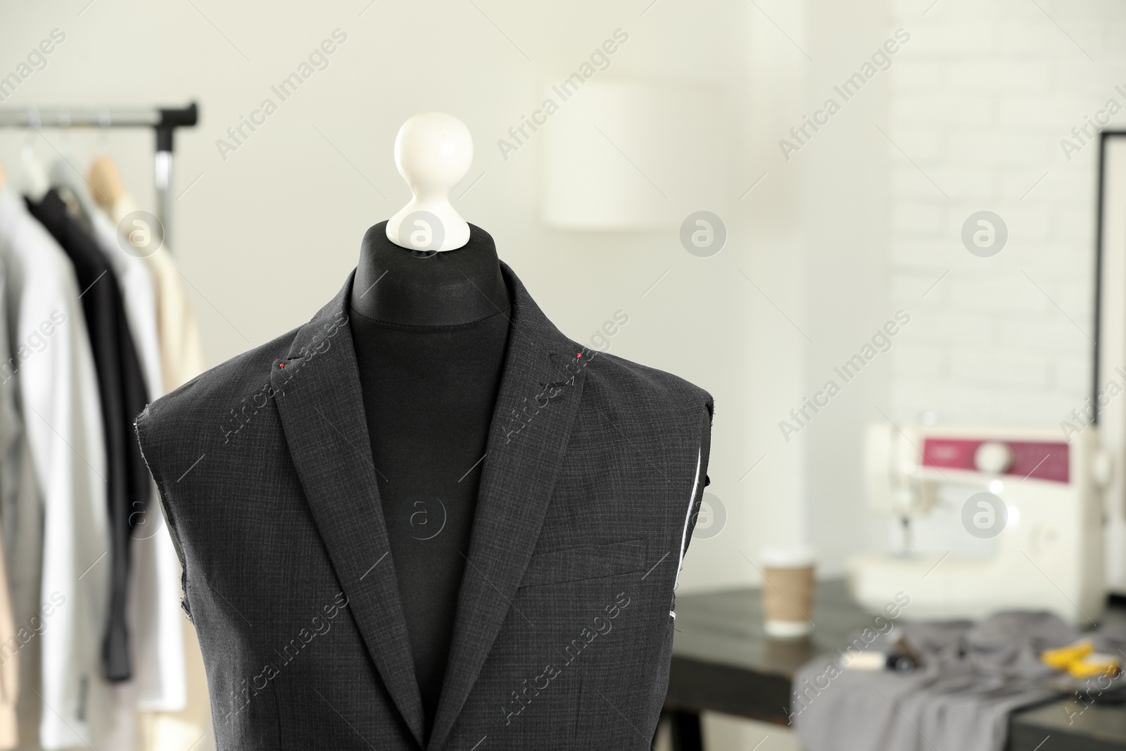 Photo of Mannequin with unfinished jacket in tailor shop, space for text