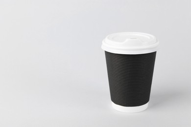 Black paper cup with plastic lid on light background, space for text. Coffee to go