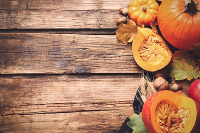 Photo of Flat lay composition with vegetables, nuts and autumn leaves on wooden table, space for text. Thanksgiving Day